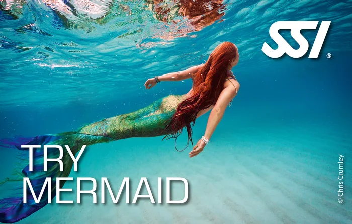 Guest trying on a mermaid monofin for the first time in sheltered shallow water in Khao Lak, Thailand during a Try Mermaid session