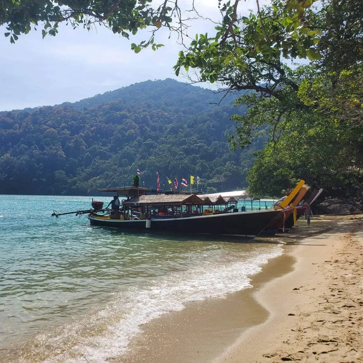 Traditional longtail boat resting beside a Surin beach