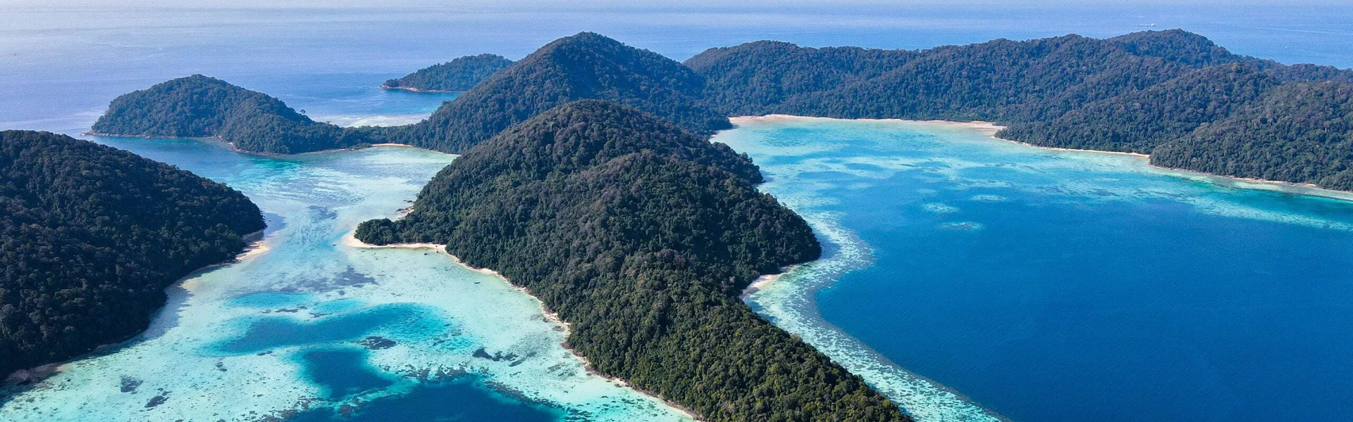 Aerial view of forested Surin Islands surrounded by clear blue Andaman Sea