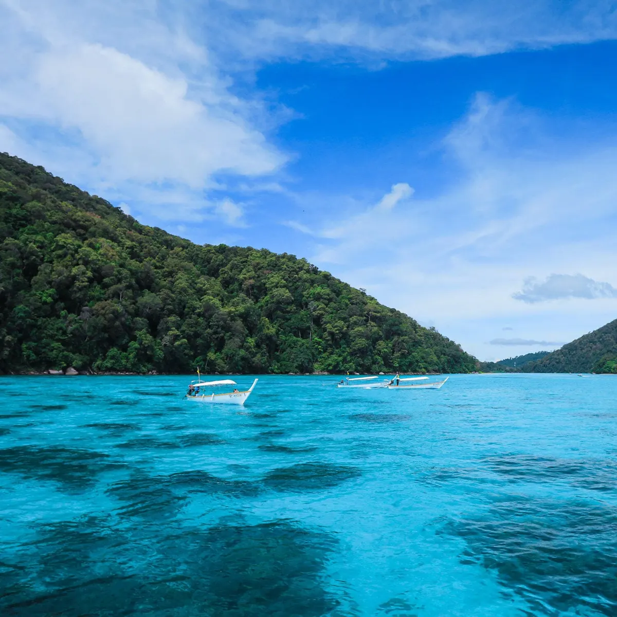 Turquoise bay with forested islands and local boats at Surin